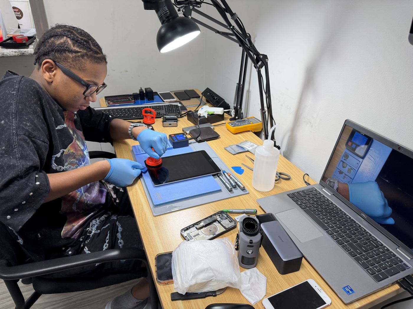 A student working on an iPad screen at the bench with the overhead camera view on a laptop