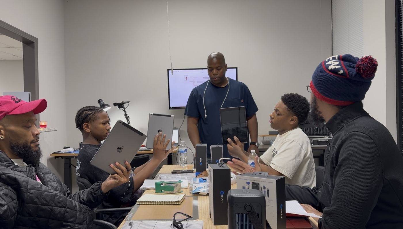 The October 2026 cohort holding their iPads with the instructor at the board